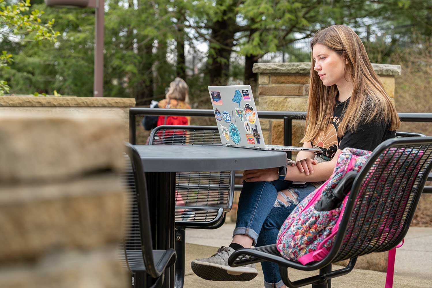 female student sitting outside with laptop
